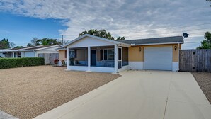 A single-story house with a covered porch, a garage, and a gravel driveway. - Stylish Port Richey Home ~ 8 Mi to Beach Park! (Port Richey)