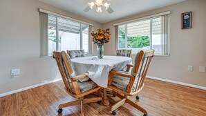 A dining room with a round table, wooden chairs, a ceiling fan, and a vase of flowers. - Stylish Port Richey Home ~ 8 Mi to Beach Park! (Port Richey)