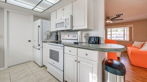 A compact kitchen with white cabinets, a microwave, a toaster, and a stainless steel trash can. - Stylish Port Richey Home ~ 8 Mi to Beach Park! (Port Richey)