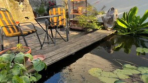 A patio area with a wooden deck, chairs, and potted plants.
