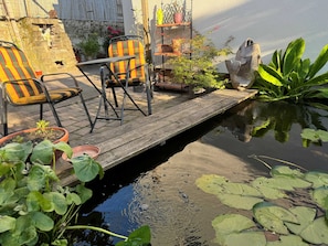 Uma área de pátio com deck de madeira, cadeiras e plantas em vasos.