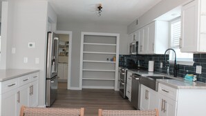 A modern kitchen with white cabinets, stainless steel appliances, and a black tiled backsplash.