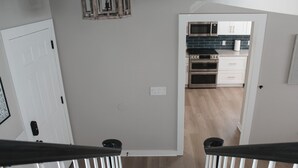 A modern kitchen with stainless steel appliances, white cabinetry, and a wooden floor.