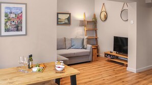 Un salon moderne avec un canapé gris, une table basse en bois et un meuble pour la télévision.