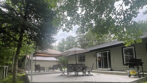 A covered outdoor patio with a wooden deck, outdoor furniture, and a barbecue grill. - Newly Remodeled Family-Friendly Home in Woodruff Close to Everything (Woodruff)