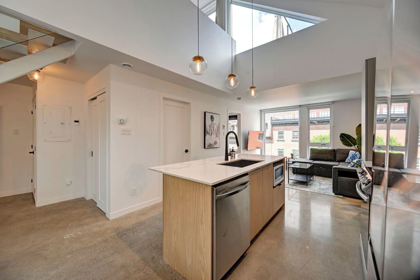 Una cocina moderna con una isla central, un rincón de comedor con sofá y un amplio ventanal que proporciona luz natural.