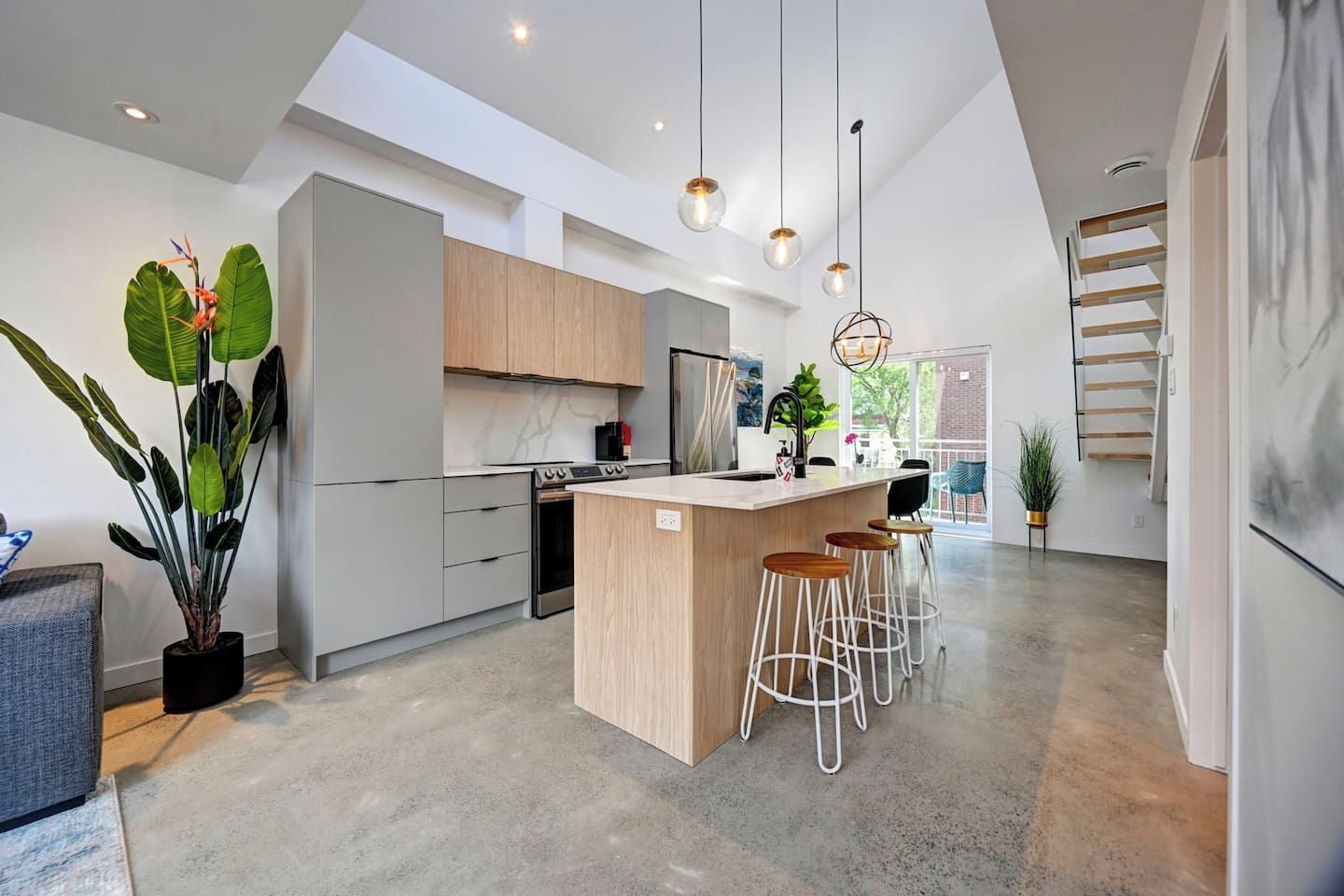 A modern kitchen with a central island, bar stools, and pendant lighting.