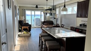 Une cuisine spacieuse dotée d’un grand îlot central, de meubles de rangement en bois foncé et d’un éclairage suspendu.