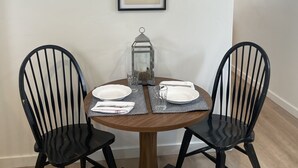 Une table à manger avec deux chaises, un tableau encadré au mur et une lanterne posée sur la table.