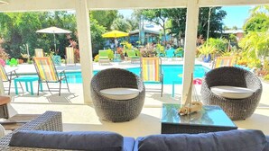 A poolside area with wicker furniture, including two chairs and a sofa, and a small table with a dog. - Fun in the Sun (Naples)