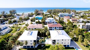 A coastal residential area with multiple two-story buildings, a swimming pool, and a view of the ocean. - Newly updated 2B/2B condo, walk to the beach! (Holmes Beach)