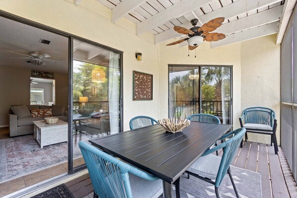 An outdoor patio with a dining table, chairs, and a ceiling fan.