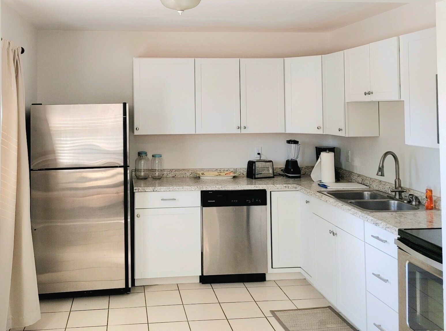 A modern kitchen with white cabinets, stainless steel appliances, and a granite countertop.