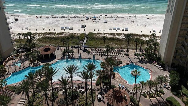 A resort with a pool area, beach access, and a view of the ocean.