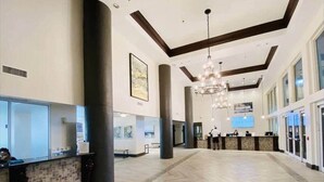 A spacious lobby with a herringbone floor pattern, a reception desk, and a chandelier.