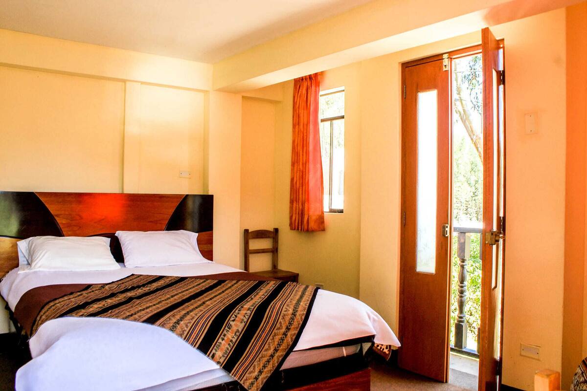 Ein Schlafzimmer mit einem großen Bett, einem hölzernen Kopfteil, einem Sessel und einer Tür zu einem Außenbereich.