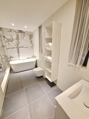 Une salle de bain moderne avec une baignoire sur pieds, des toilettes et un meuble-lavabo avec un évier.