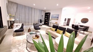 A modern living room with a sofa, armchairs, a coffee table, and a dining area. - Victor Regents Apartment (Accra)
