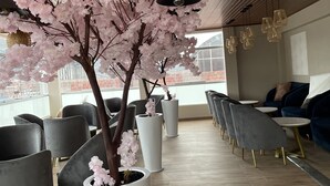 A modern interior with a large artificial cherry blossom tree, seating area with chairs and tables, and pendant lighting. - HOTEL EL ALAMO EJECUTIVO & SPA (Cusco)