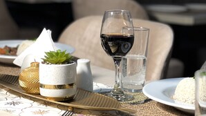 A table set with a glass of red wine, a plate of white rice, a small potted plant, and decorative items. - HOTEL EL ALAMO EJECUTIVO & SPA (Cusco)