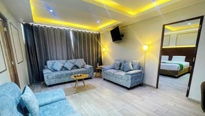 A modern living room with two sofas, a coffee table, and a TV mounted on the wall. - HOTEL EL ALAMO EJECUTIVO & SPA (Cusco)