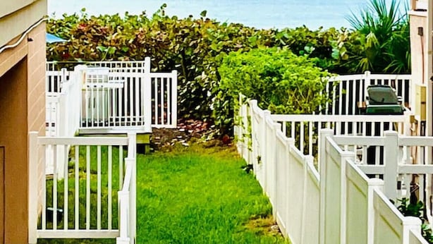 A narrow pathway leading to a balcony with a view of the ocean. - `Dunes` Gulf-View Historic Beachside Cottage 1/1 (Indian Rocks Beach)