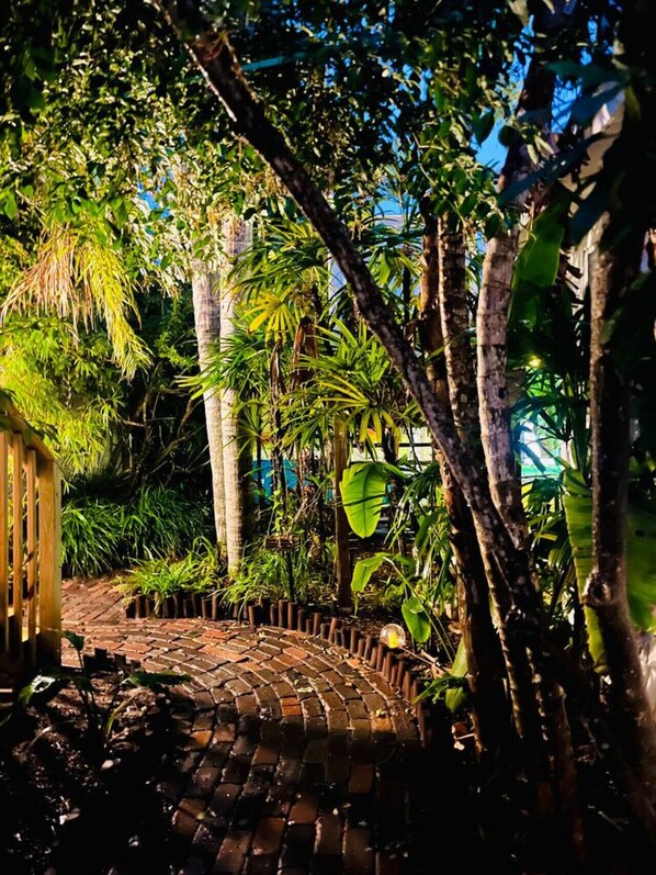 Um caminho no jardim, ladeado por vegetação tropical exuberante.