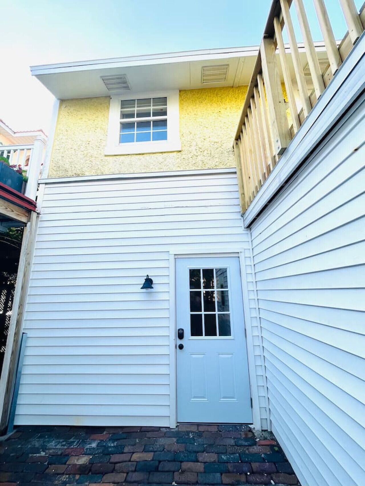 Un bâtiment à deux étages, à l’extérieur blanc, avec une porte d’entrée et une petite fenêtre située au-dessus de la porte.