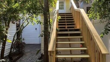 Staircase leads to a small elevated structure surrounded by lush greenery and interlocking brick paving.