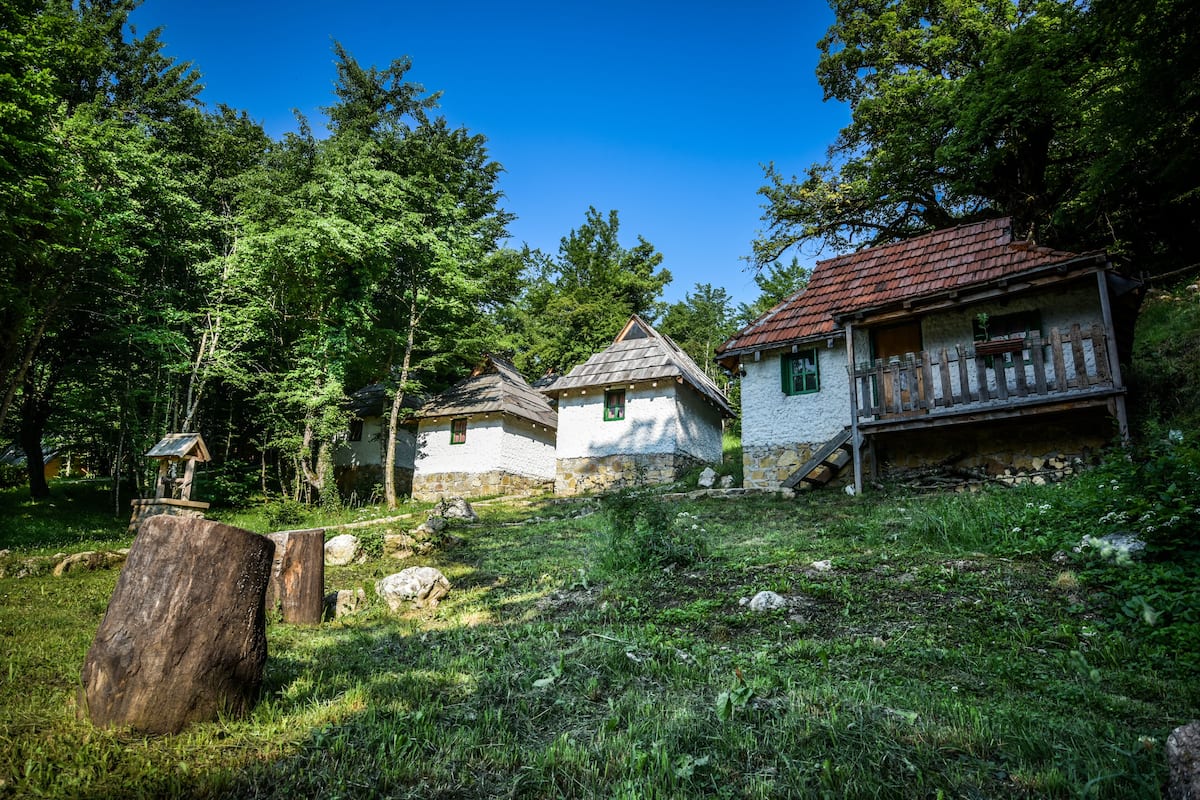 A rustic cabin with a stone exterior, a wooden deck, and a small porch.