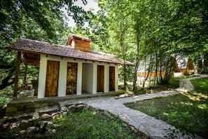 A rustic building with a tiled roof, wooden doors, and a stone pathway leading to it.