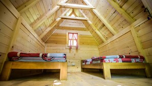 A wooden cabin with two bunk beds, a window with red curtains, and a wooden ceiling with a triangular peak. - Camp Divlja Rijeka (Foca)