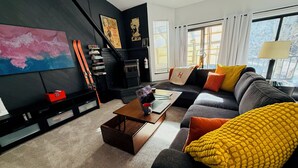 Una sala de estar moderna con un sofá negro, una mesa de centro y un cuadro grande en la pared.