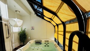 Un jacuzzi con un panel de control, un cartel de ‘No Diving’ y una planta en una habitación con un dosel amarillo.