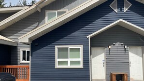 A two-story house with a dark blue exterior, white trim, and a front door with a small porch area. - Spacious Town Home, Sleeps 8, Walk to Gondola! (Whistler)