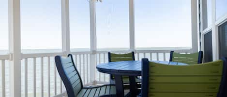 A covered outdoor area with a wooden deck, white railings, and a table with chairs.