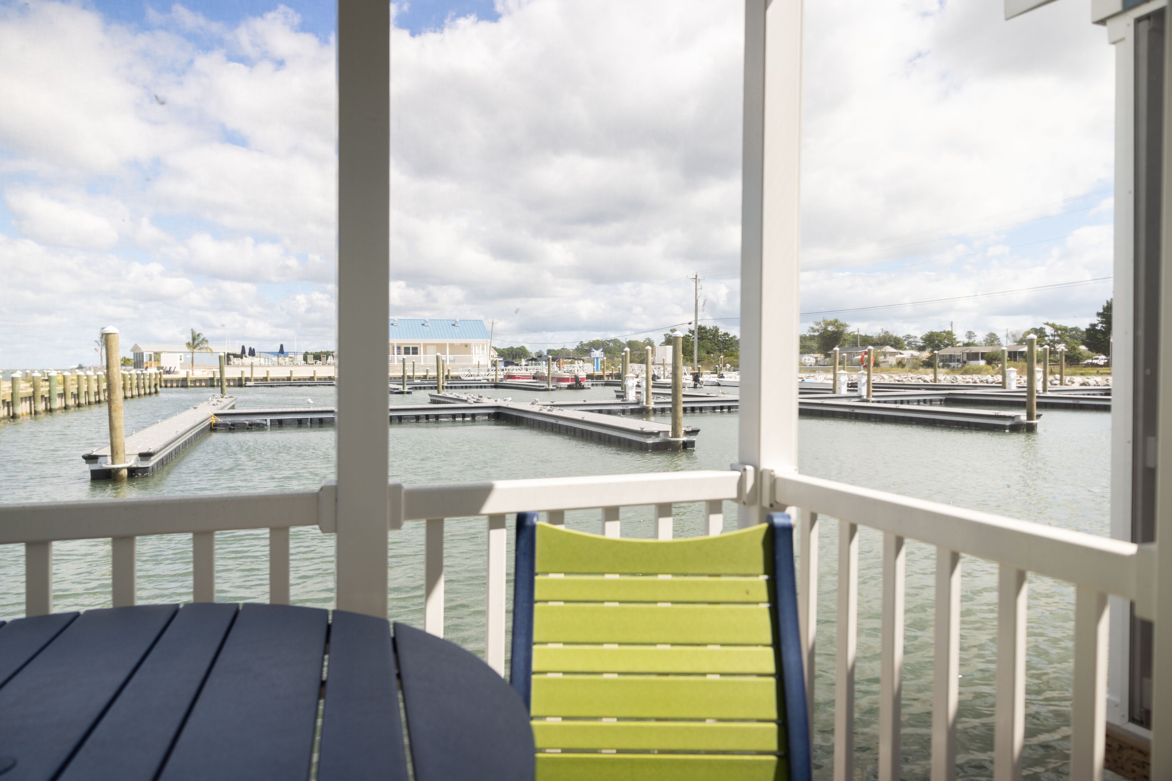 A view from a covered deck with a table and chairs, overlooking a marina with docks and boats.