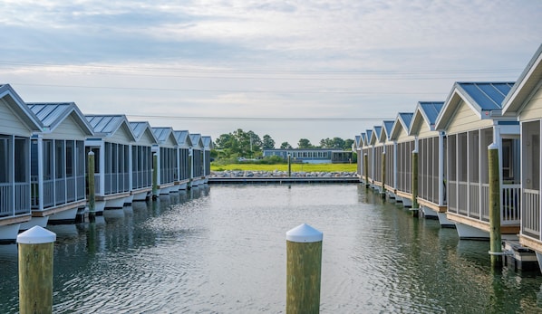 Une rangée de charmantes maisons de vacances situées au bord de l’eau, avec un quai au milieu.