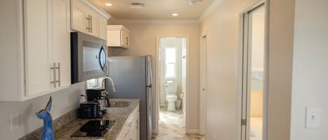 A modern kitchen with granite countertops, stainless steel appliances, and white cabinetry.
