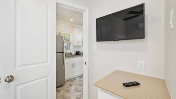A hallway leading to a kitchen with a TV mounted on the wall.