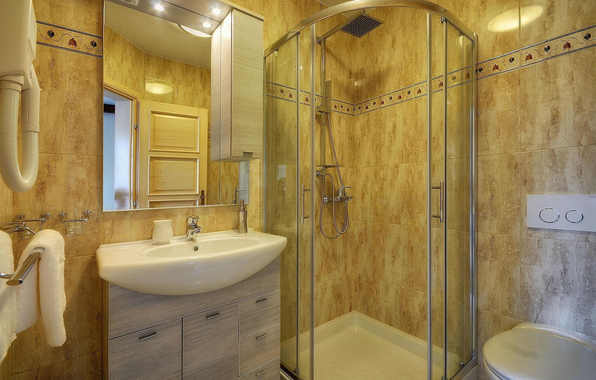 A bathroom with a glass-enclosed shower, a sink, and a toilet.