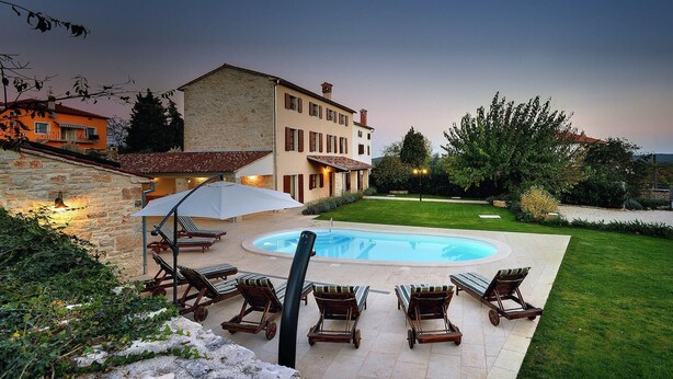 A pool area with lounge chairs and a stone building in the background.