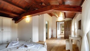 A bedroom with a wooden ceiling, a bed with white linens, a bedside table, and a nightstand.