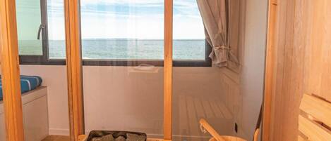 A wooden sauna room with a bench, a bucket, and a tray of stones.