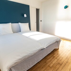 Un dormitorio con una cama, una puerta y un aplique en la pared.