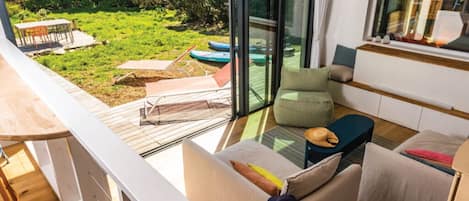 A modern interior with a balcony overlooking a grassy area and the sea.