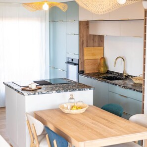 Una cocina moderna con una isla central, un lavamanos con grifo dorado y una mesa de madera con sillas.