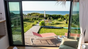 Une chambre moderne dotée d’une grande porte-fenêtre coulissante qui donne sur une terrasse offrant une vue sur la mer.