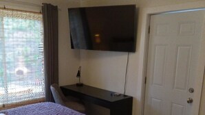 A bedroom with a bed, a desk, a television, and a door. - Clean Private Bedroom,Bathroom. Private entrance. Lovely Gated Neighborhood.     (Vista)