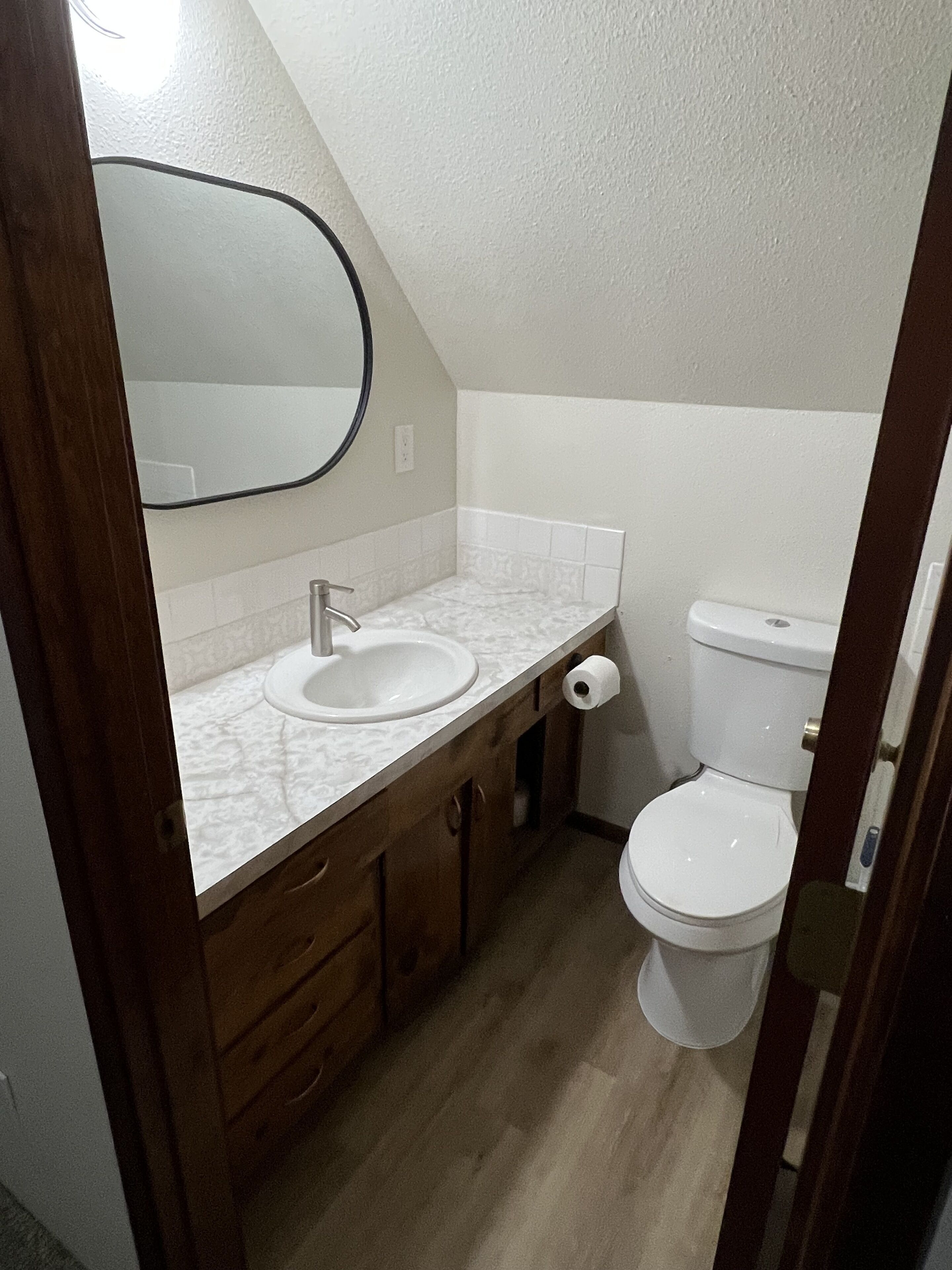 A bathroom with a white sink, mirror, and toilet.